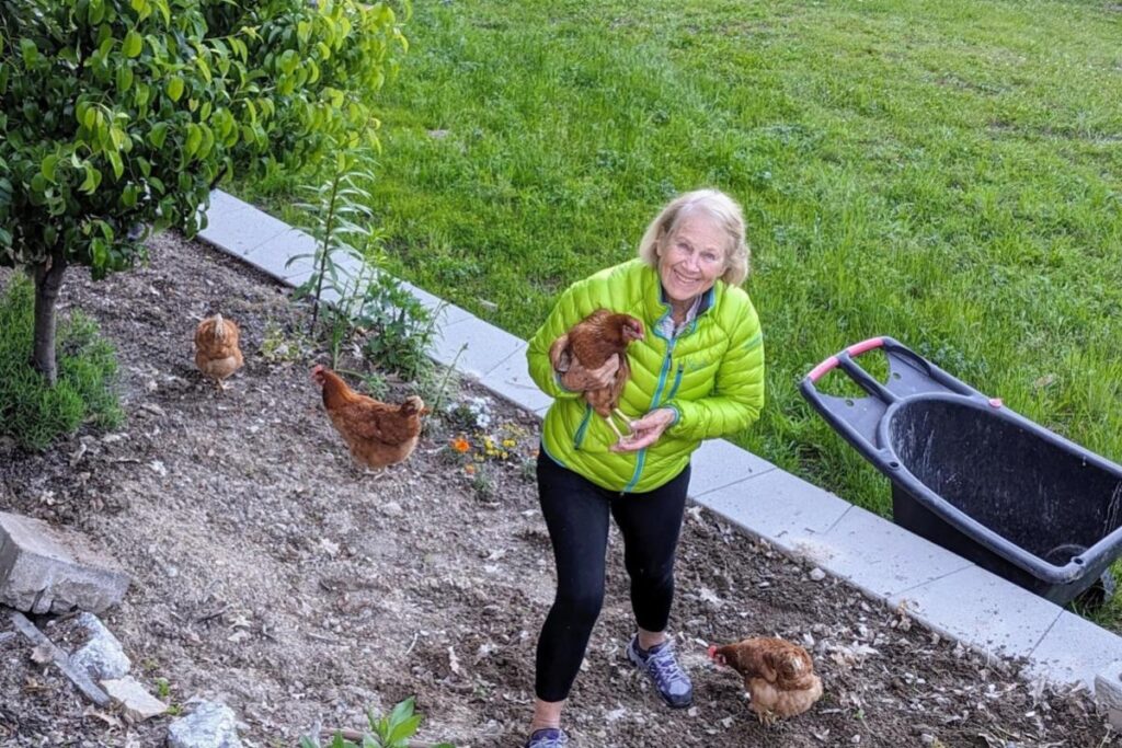 Home A smiling woman holding a chicken in the garden at Christina Lake House.